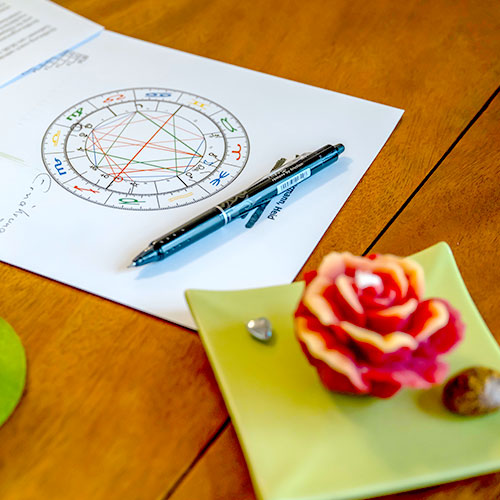 Horoskopzeichnung mit Stift und Blüte auf dem Tisch
